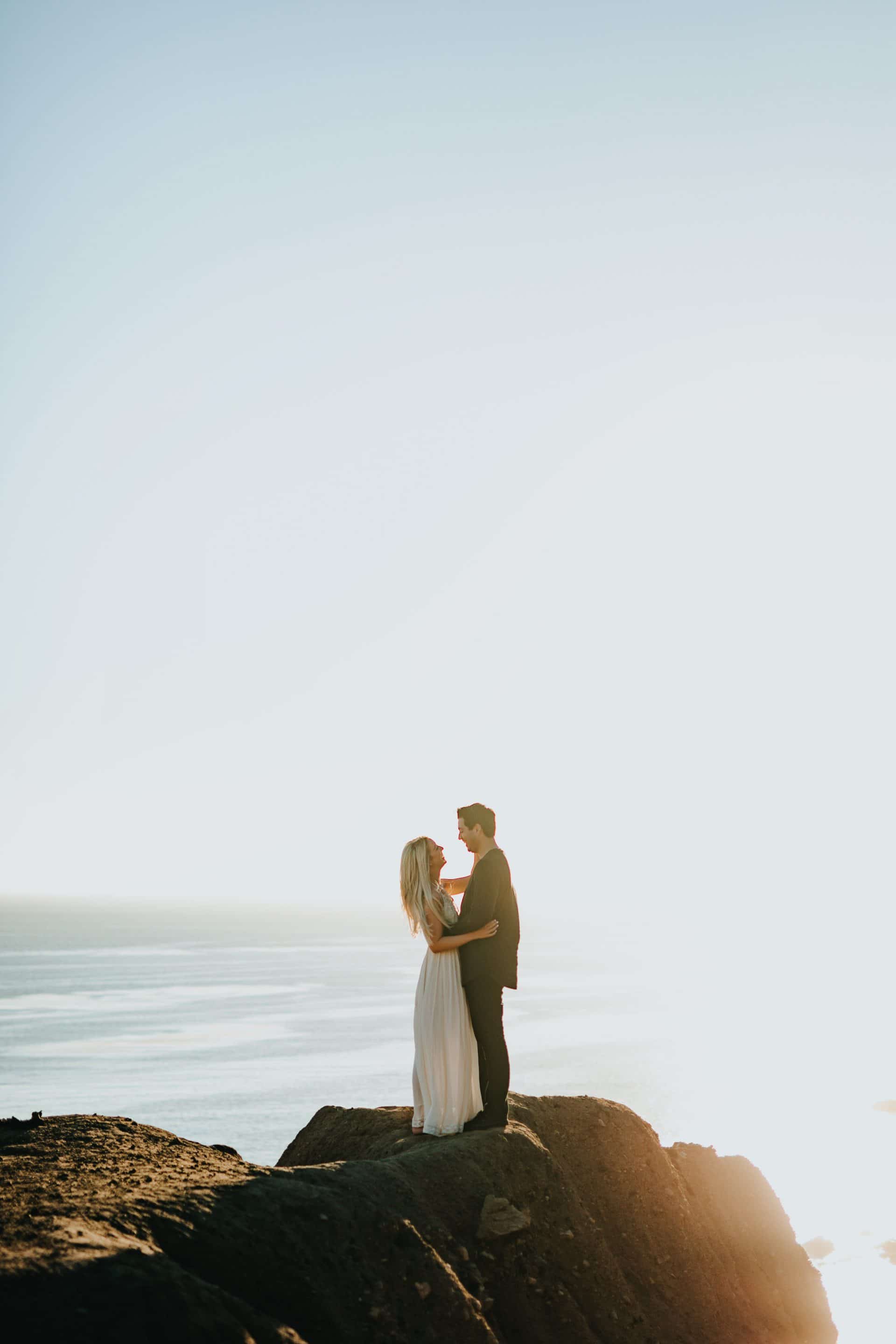 Married couple holding each other standing near the ocean