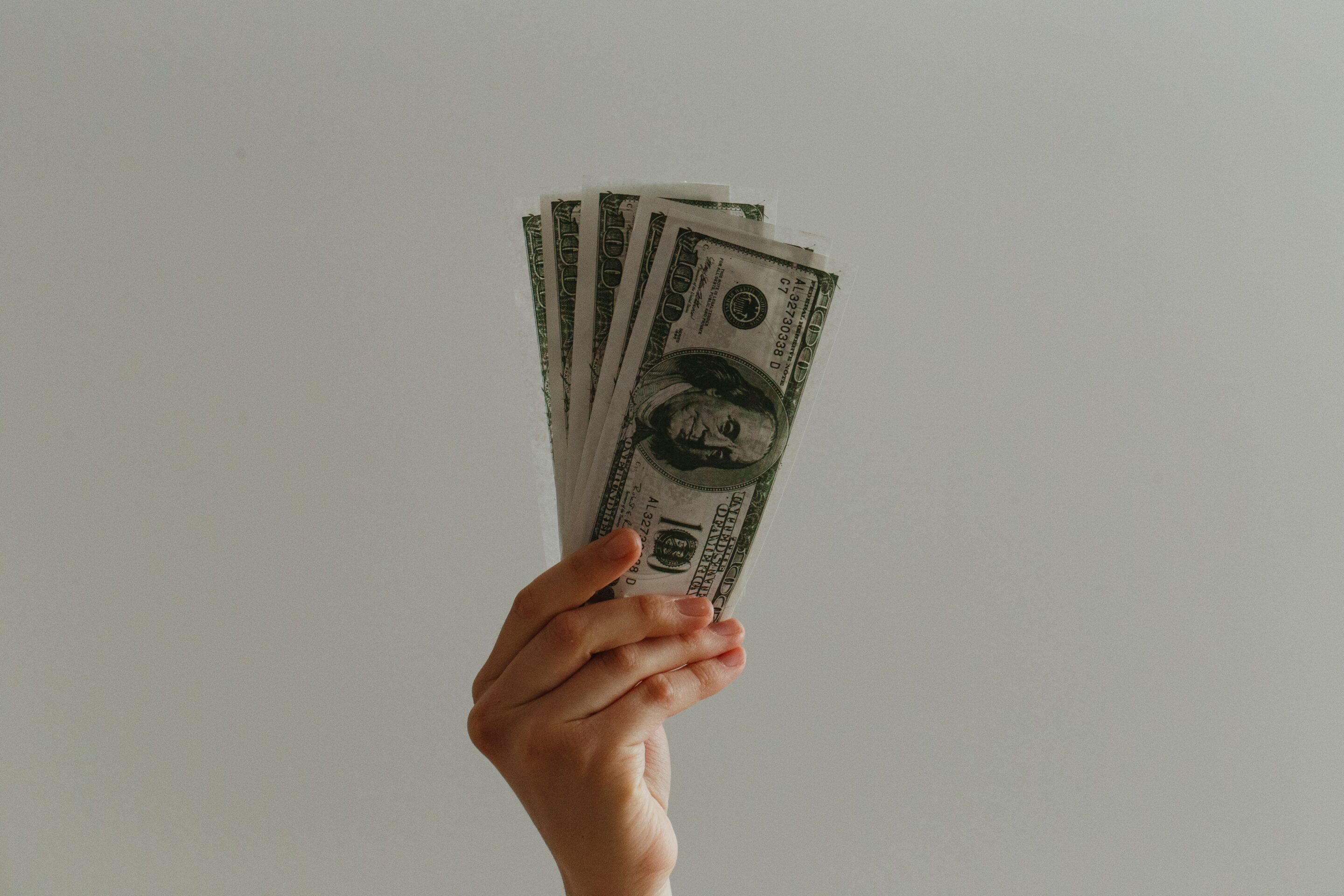 image of hand holding money with light color background